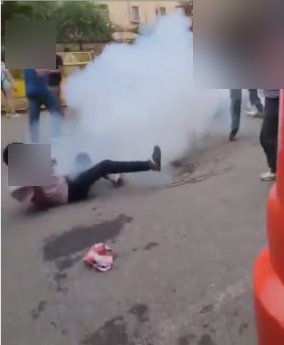 A tear gas shell discharging beside a protester who is on the ground