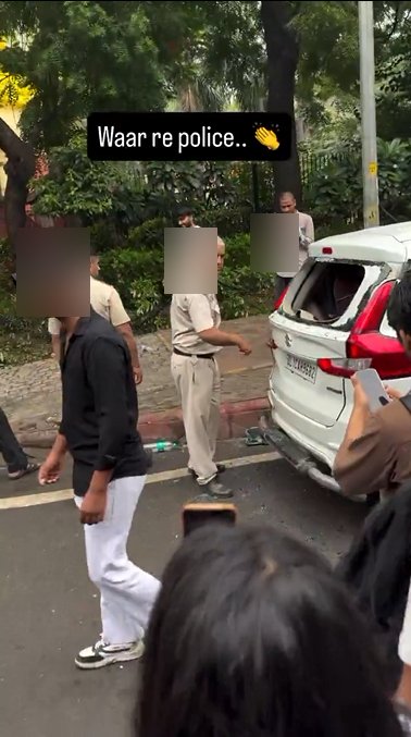 Police personnel beside a car with its rear window freshly smashed